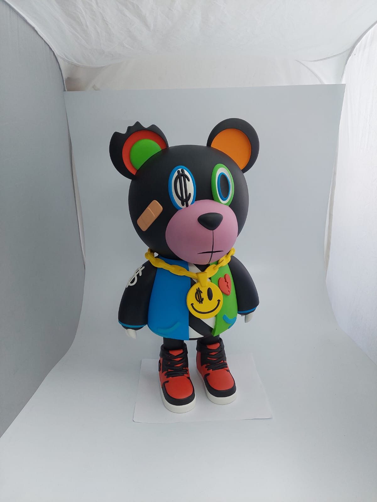 Art toy de oso negro con cadena de oro y tenis rojos, fabricado por Haxu3D